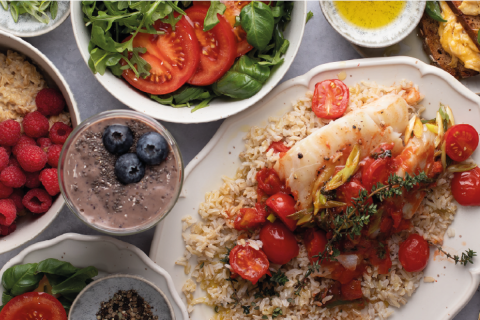 Verschiedene gesunde Gerichte mit Fisch, Reis, Salat und Obst.