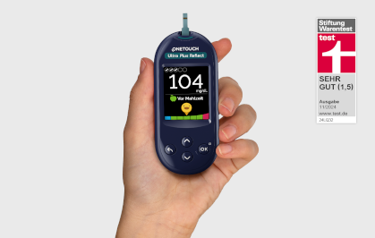 Hand hält ein Blutzuckermessgerät mit Wert 104 mg/dl.